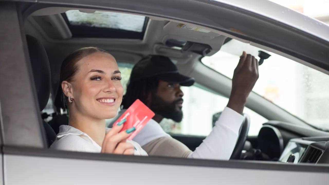 a couple in a car together. women holding up her CAA Everyday Membership card