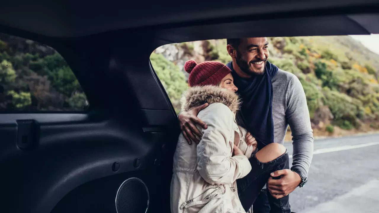 couple standing outside of their vehicle smiling