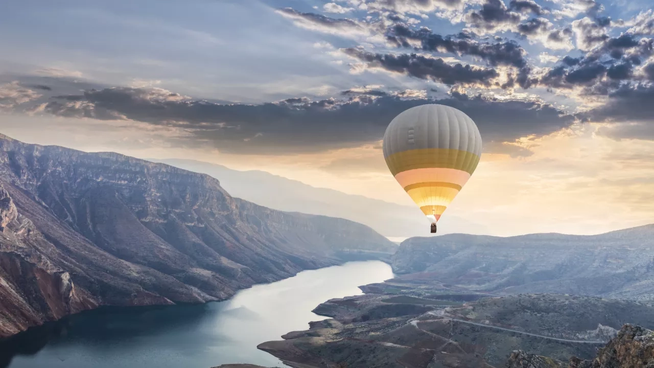 Hot air balloon floating over water in Botan Canyon, Turkey