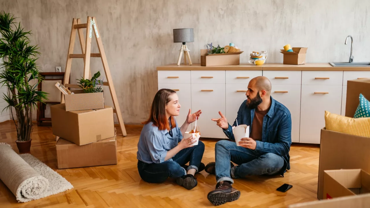 young couple eating takeout on floor of new apartment