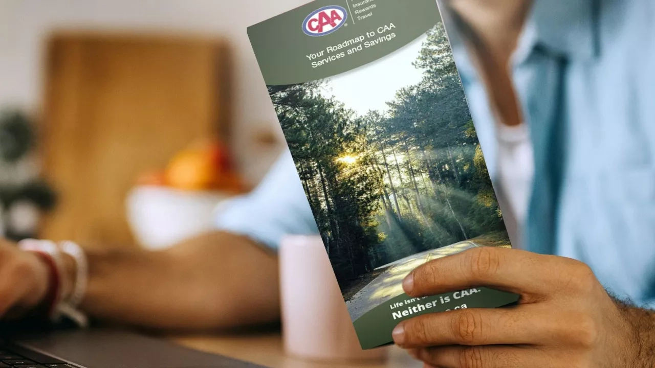 man on his laptop and holding a CAA Membership handbook