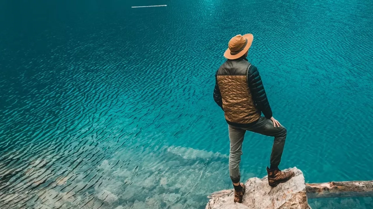 Man hiking in Canada standing on a rock overlooking a lake