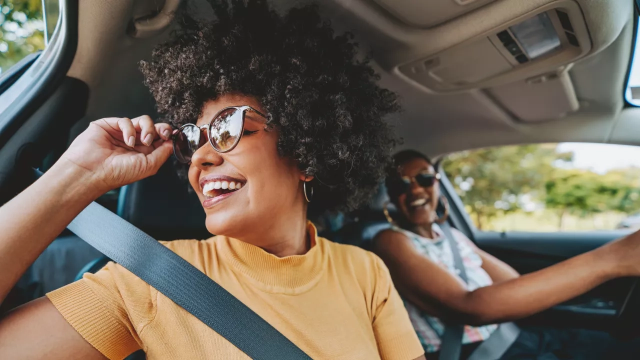 Two women driving in a car on a road trip 