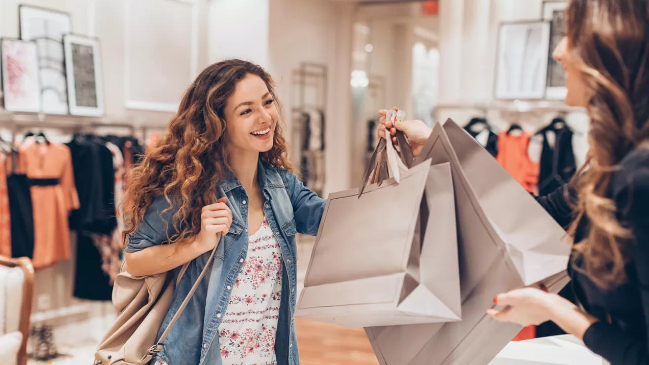 Cashier hands woman shopping bags after making purchase at store