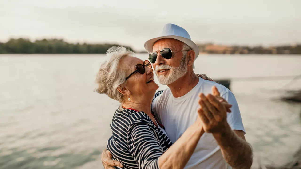 senior couple and smiling man and woman standing in sea and dancing