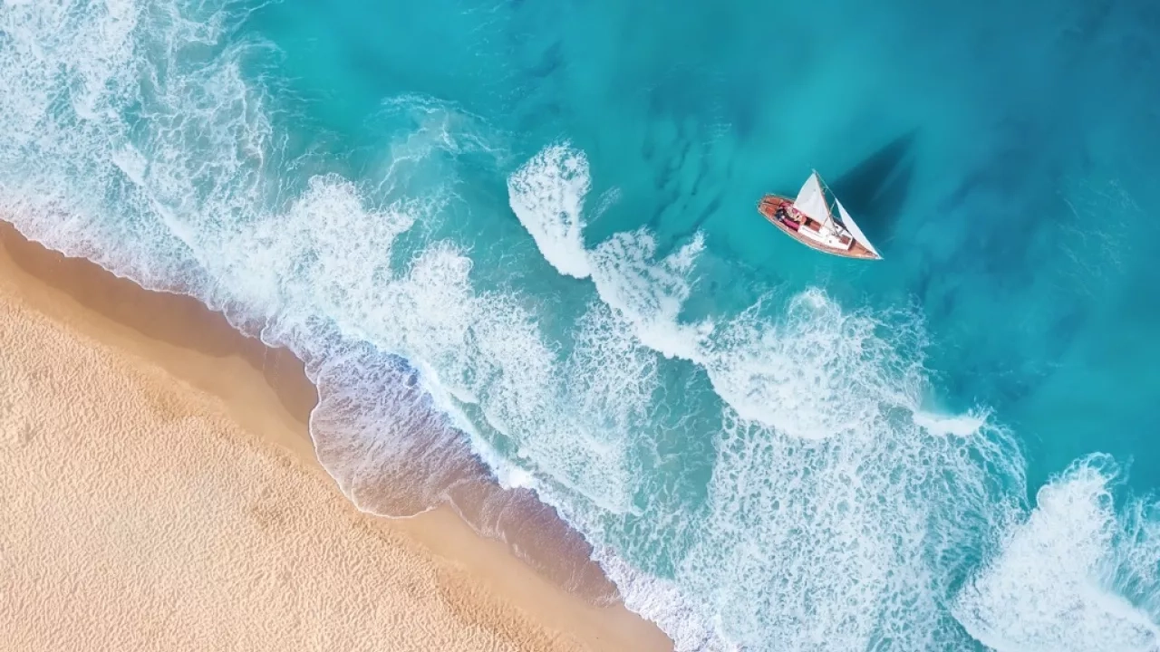 Aerial shot of a sailboat alongside the coast in the Caribbean