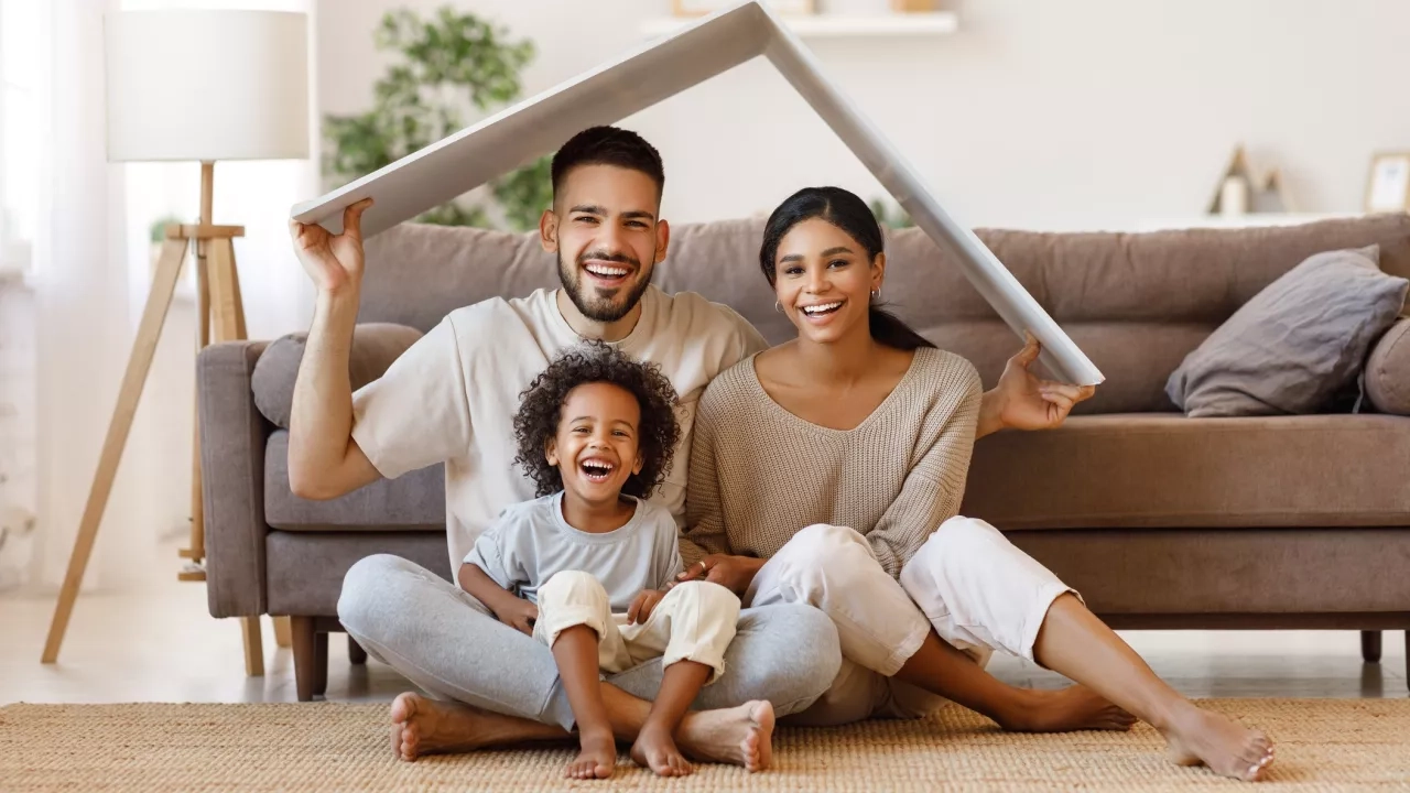 Happy family under fake cardboard roof in living room