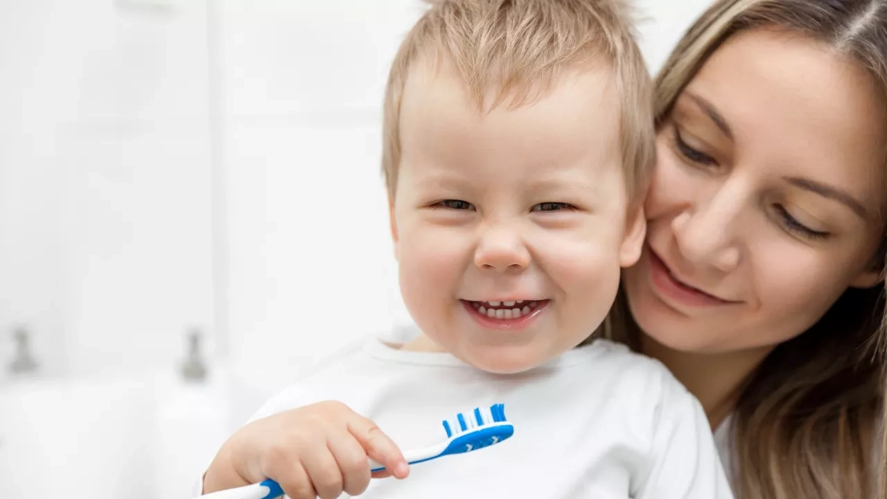 Mother teaching son how to brush teeth