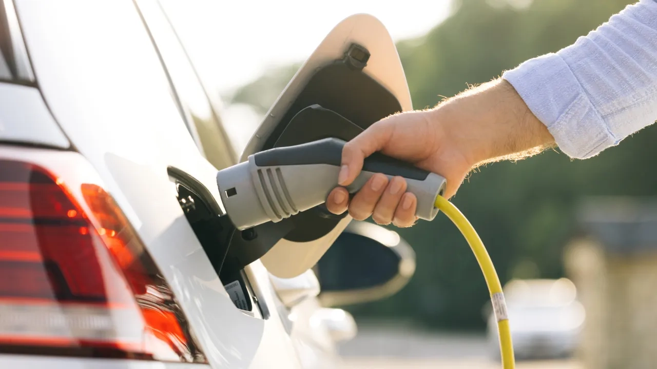 man attaching power cable to electric car