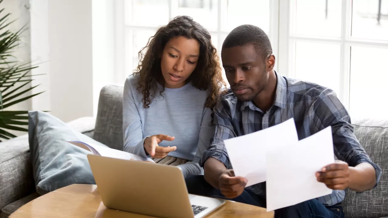 Adult couple discussing insurance documents at computer