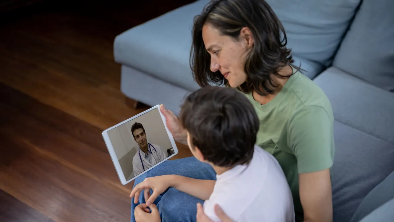 Mother and young son talking with doctor by video on a tablet