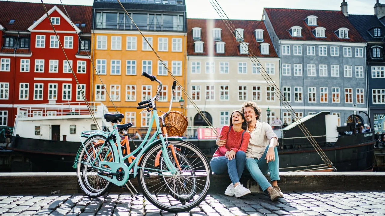 Young romantic couple with their bicycles sitting by the Stromma Canal in Copenhagen