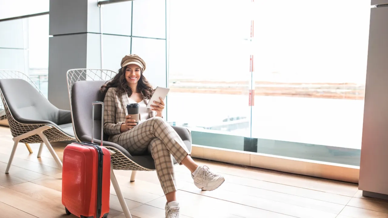 Woman smiling in an airport with her suitcase