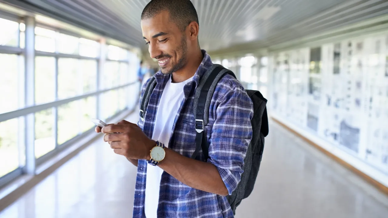 Man standing with a backpack holding a phone