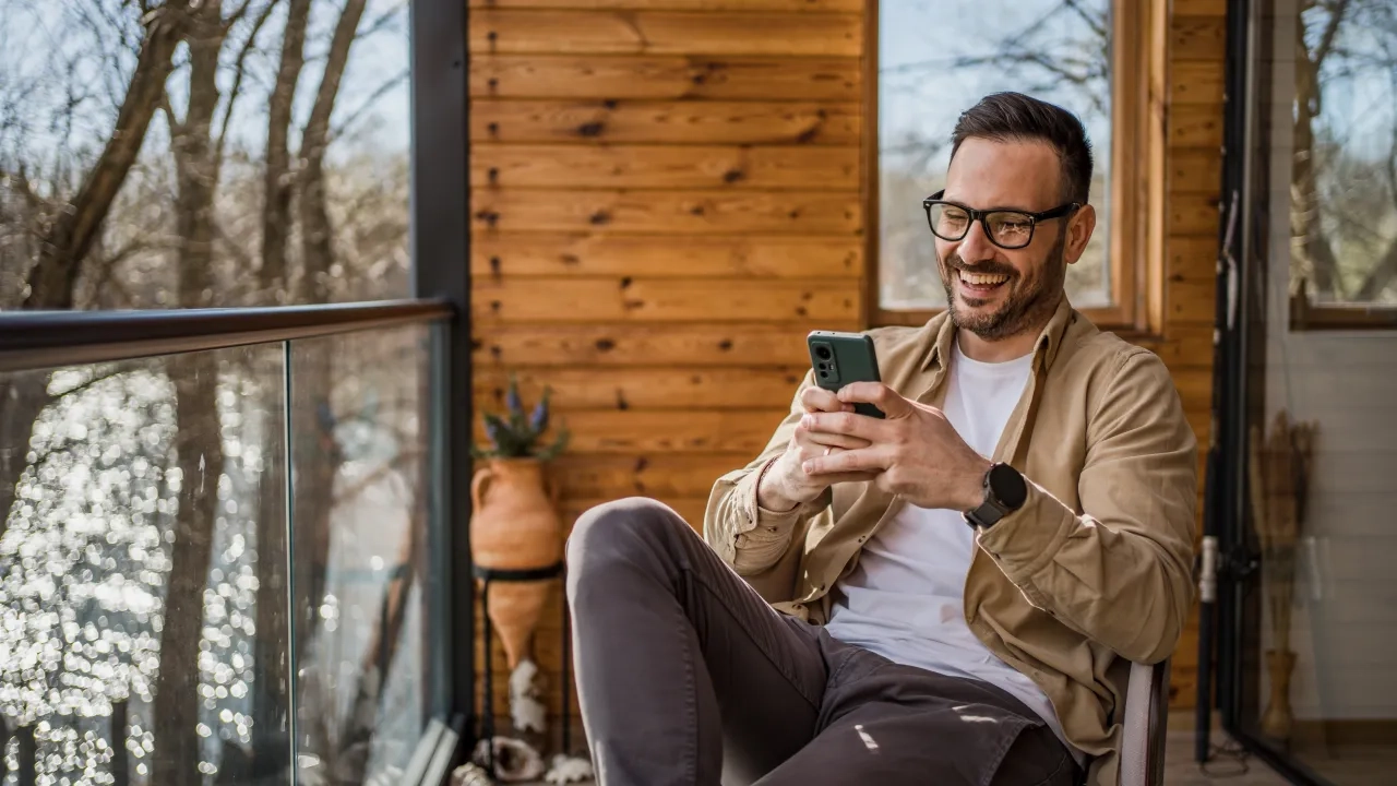A man sitting and smiling at his phone