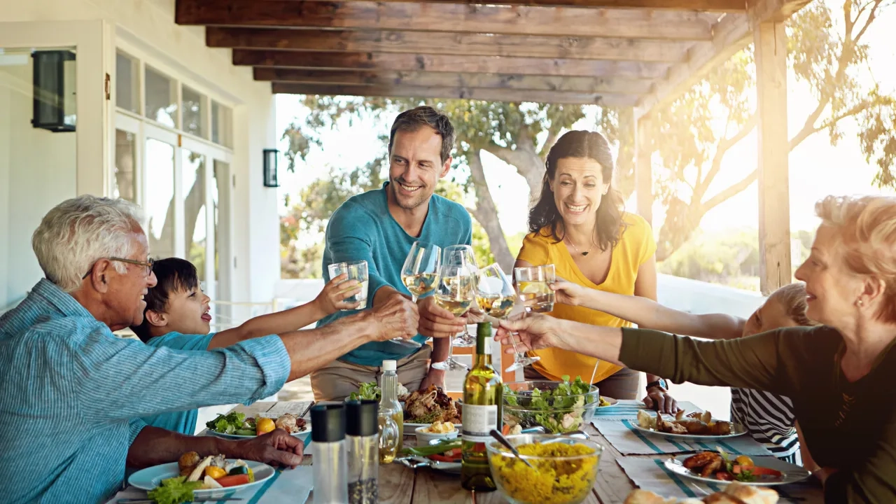 Multigeneration family celebrating outdoors and cheering glasses