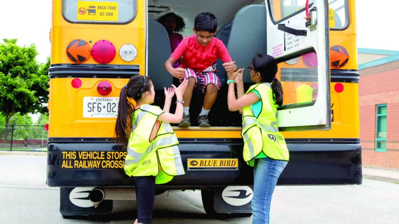 Patrollers helping a child out of a school bus