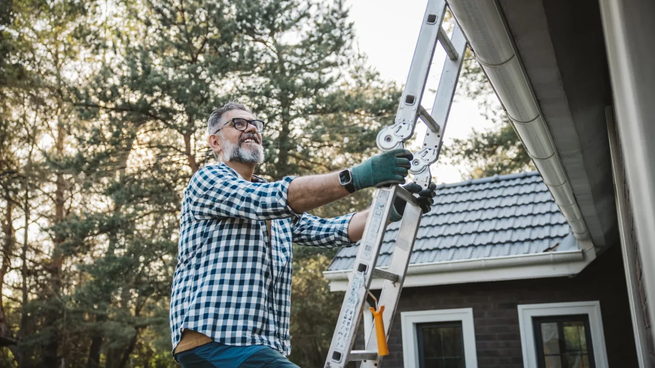 man climbing ladder to get on home roof