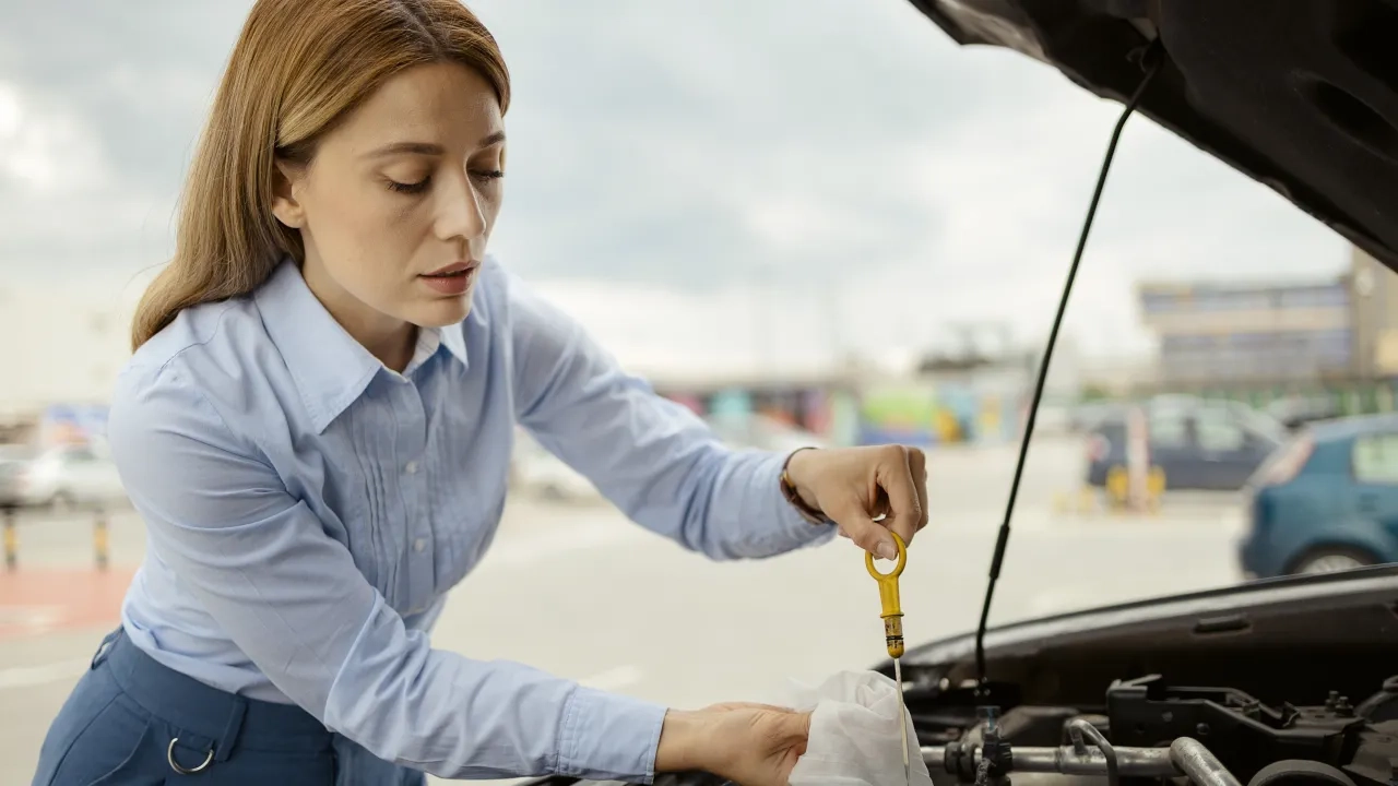 female driver checking car oil levels