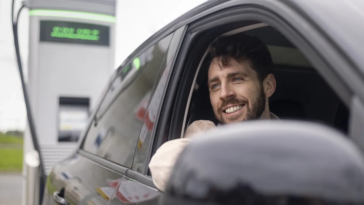 A man sitting in an electric vehicle while it is charging.
