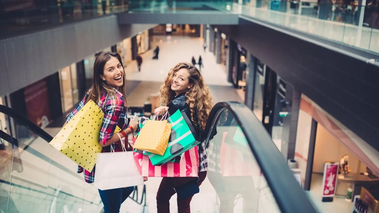 Young women moving down with escalator in the shopping mall
