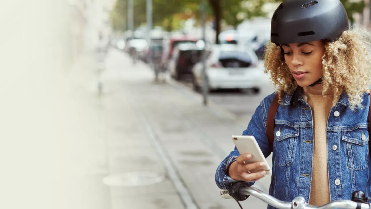 A young female stopped with her bike on her phone.