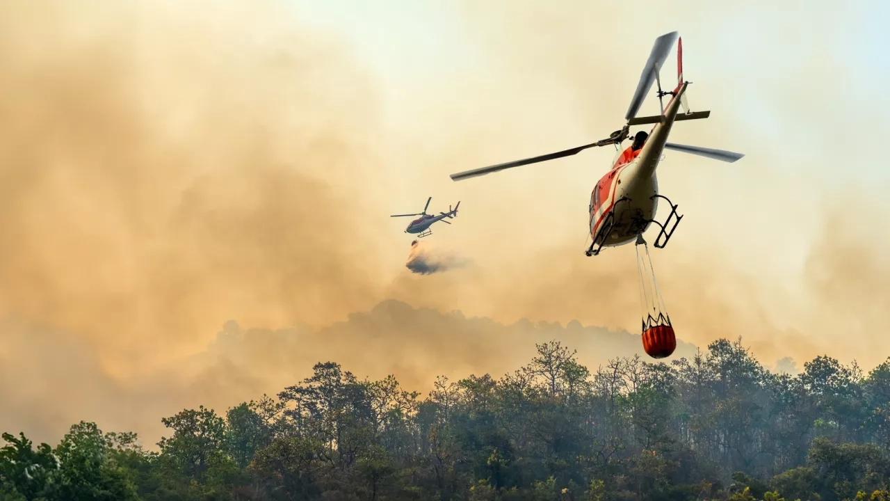 A helicopter carrying water to a wildfire