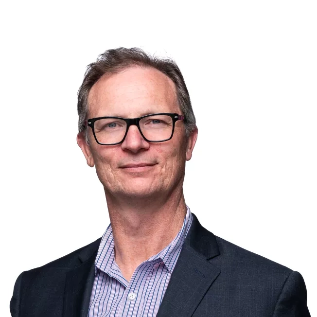 Image of a white man smiling at the camera in front of w hite backdrop