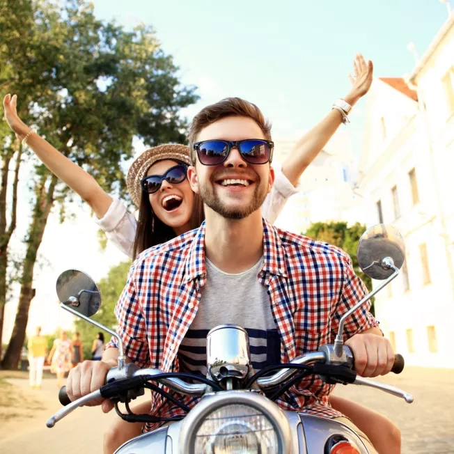 Happy young couple on scooter enjoying road in Italy