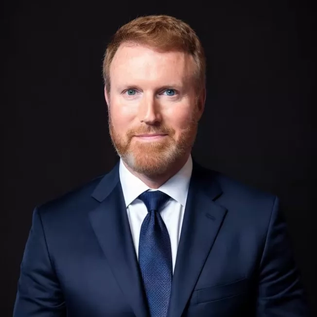 Professional headshot of a white man in front of a white backdrop