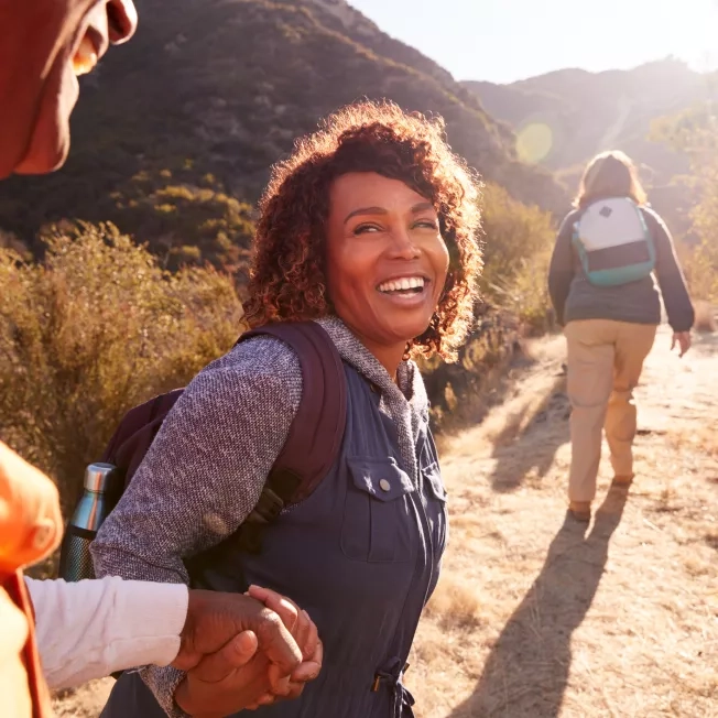 A woman looking back on a hike while laughing.