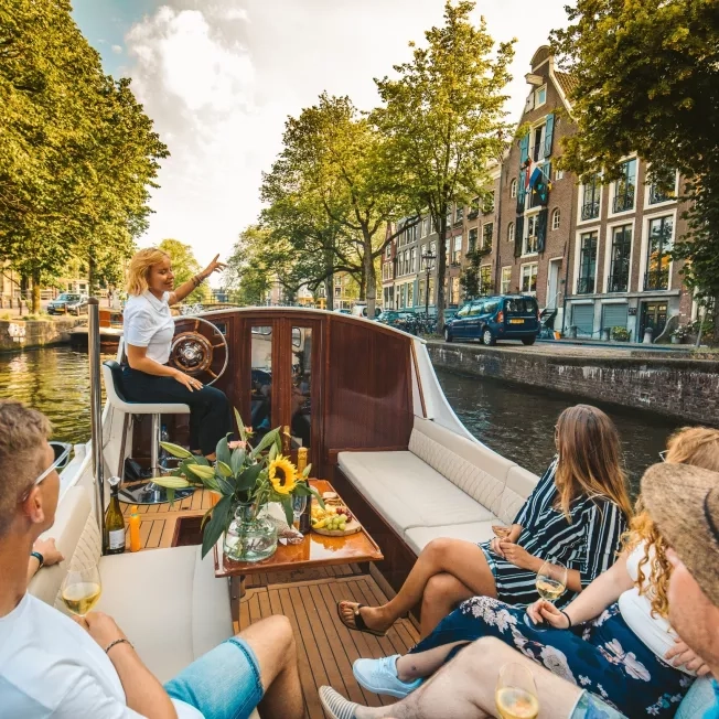 A relaxing boat trip along Amsterdam's scenic canals, featuring a small group of friends enjoying a cozy and intimate experience