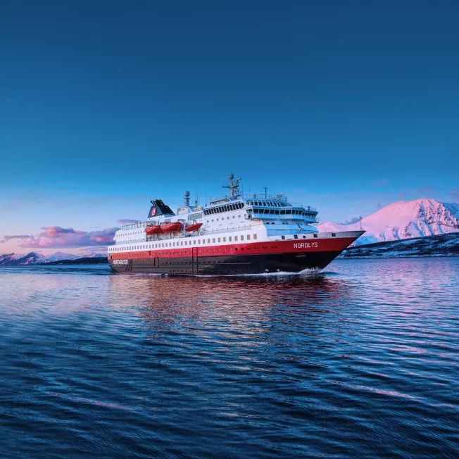 Hurtigruten Expeditions' MS Nordlys ship cruising through Norway at sunset.