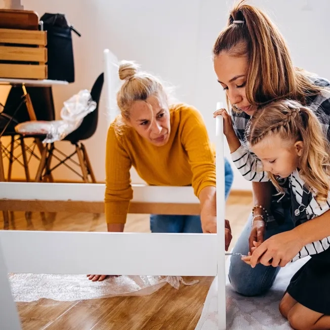 Mother, daughter, and grandmother putting together bed in a new home