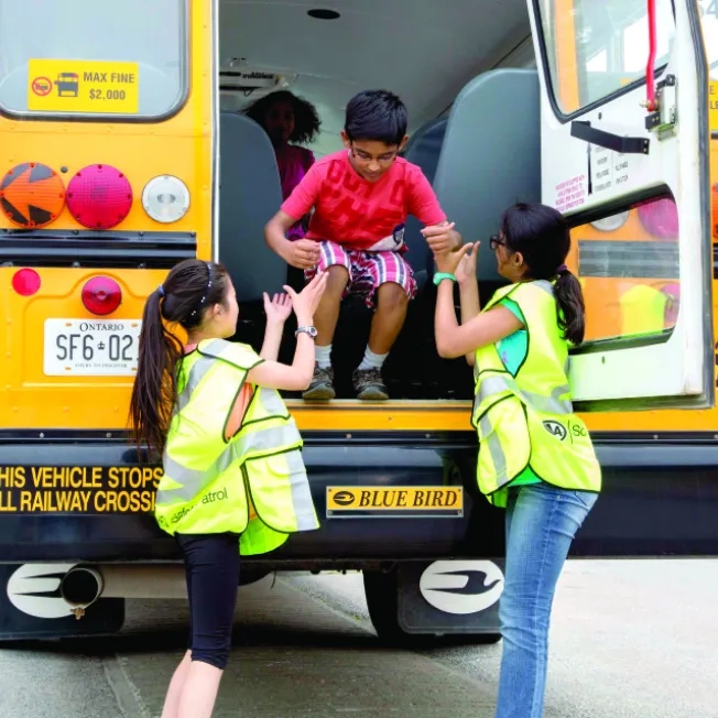 Patrollers helping a child out of a school bus