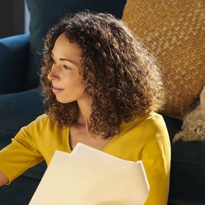 Woman reviewing her pet insurance paperwork while her dog sleeps on the couch