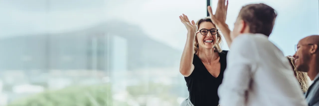 Businesswoman giving a high five to male colleague in meeting. Business professionals high five during a meeting in boardroom.