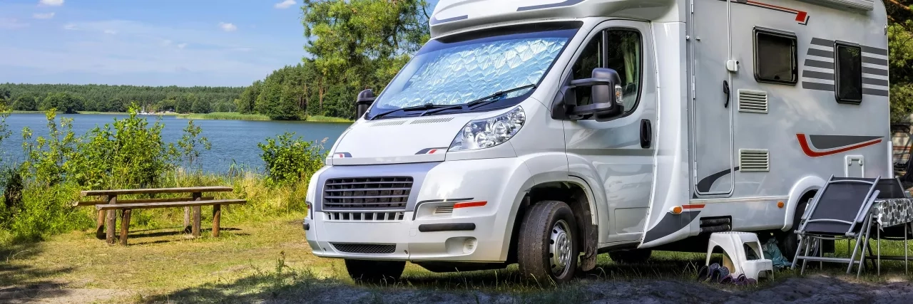 RV parked beside a picnic table and water