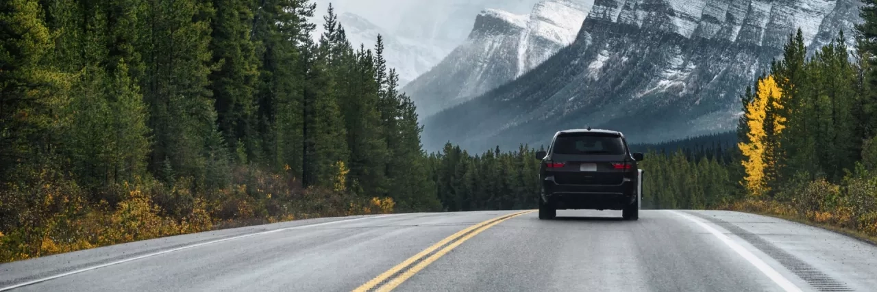 Car driving along the road with trees and mountains in the distance