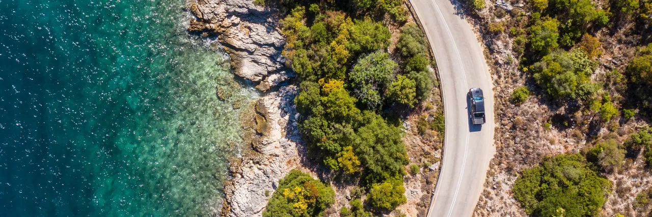 Car driving along the road with trees and water