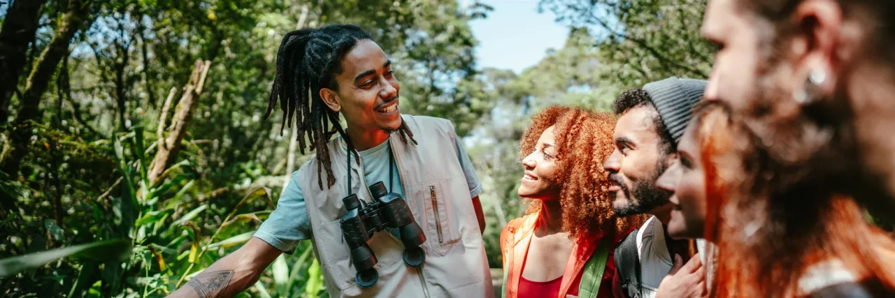 Tourist guide showing plants to a group of friends in the forest