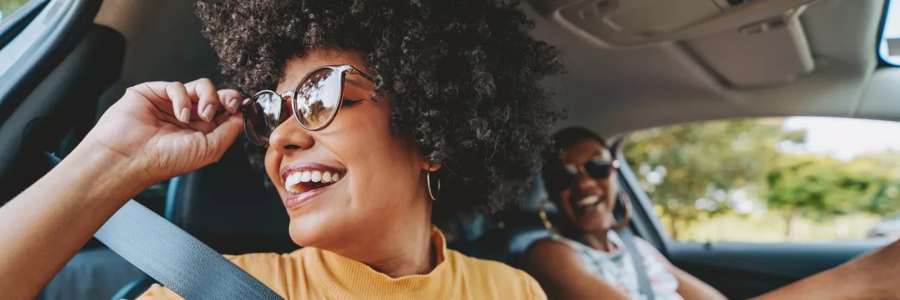 Two women driving in a car on a road trip 