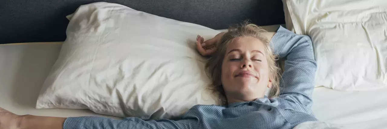 Woman laying in a hotel bed wearing pjs