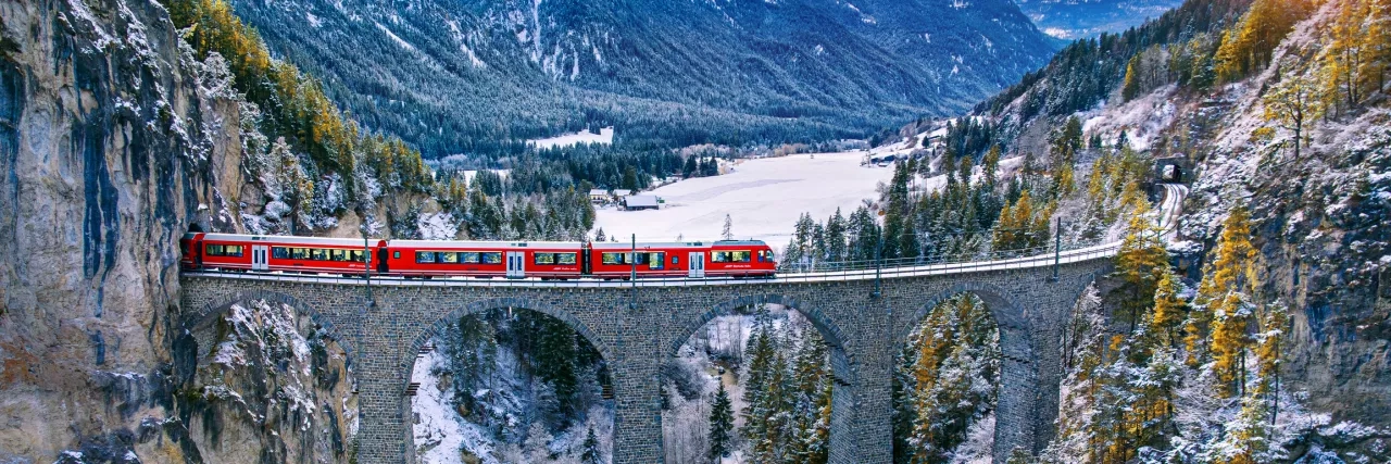 Aerial view of Train passing through famous mountain in Filisur, Switzerland. Landwasser Viaduct world heritage with train express in Swiss Alps snow winter scenery.