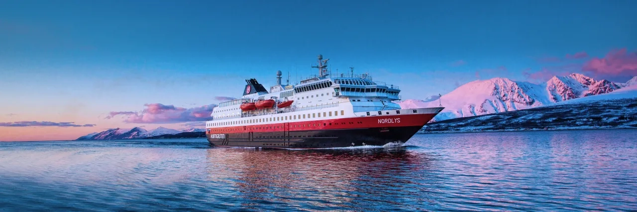 Hurtigruten Expeditions' MS Nordlys ship cruising through Norway at sunset.