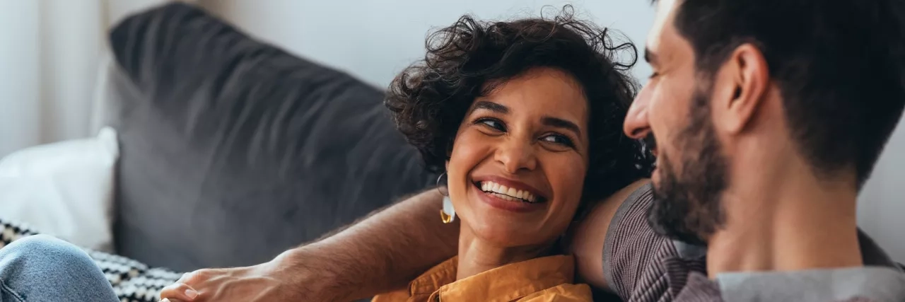 Happy couple sitting on cozy sofa at home relaxing