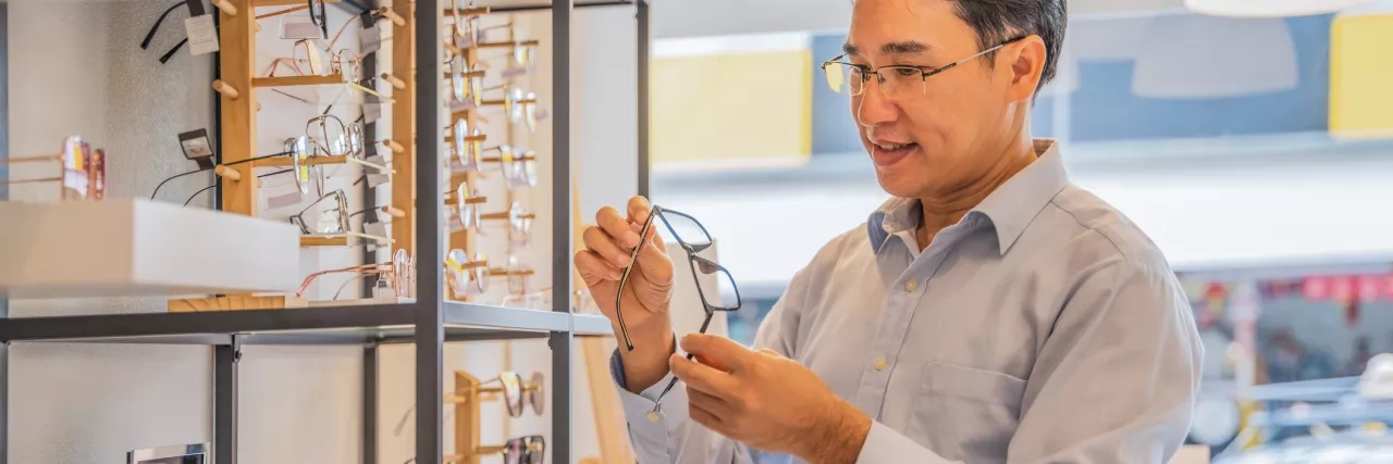 Man choosing new eyeglasses at optical store