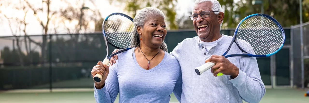 Senior couple walking off tennis court
