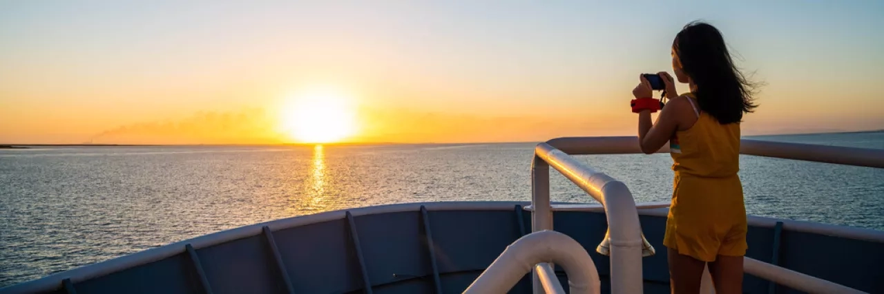 A child taking a photo off the National Geographic LIndblad Expeditions ship at sunset