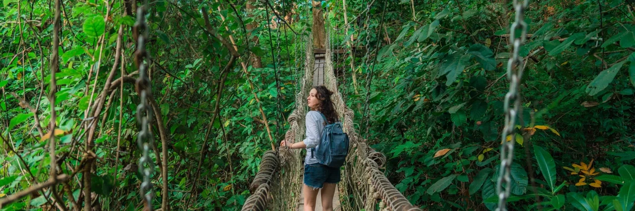 Woman walking on a rope bridge through the jungle in Costa Rica